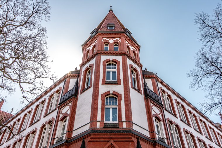 Das IFSH Hauptgebäude - Ein rot-weißes Fachwerkgebäude mit einem spitzen Turm, von unten gesehen.